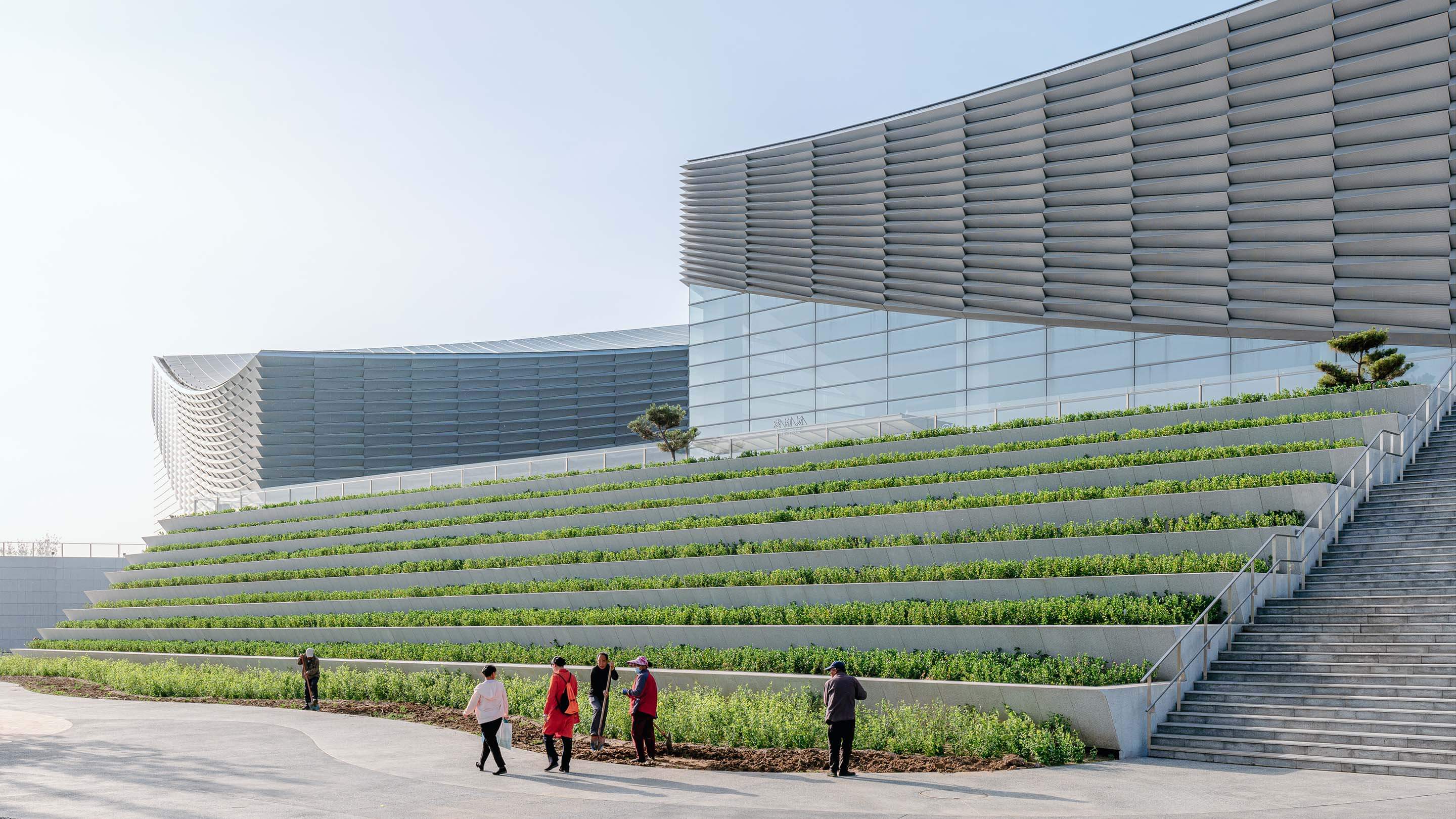 Exterior of building with plaza, landscaping, and people walking by