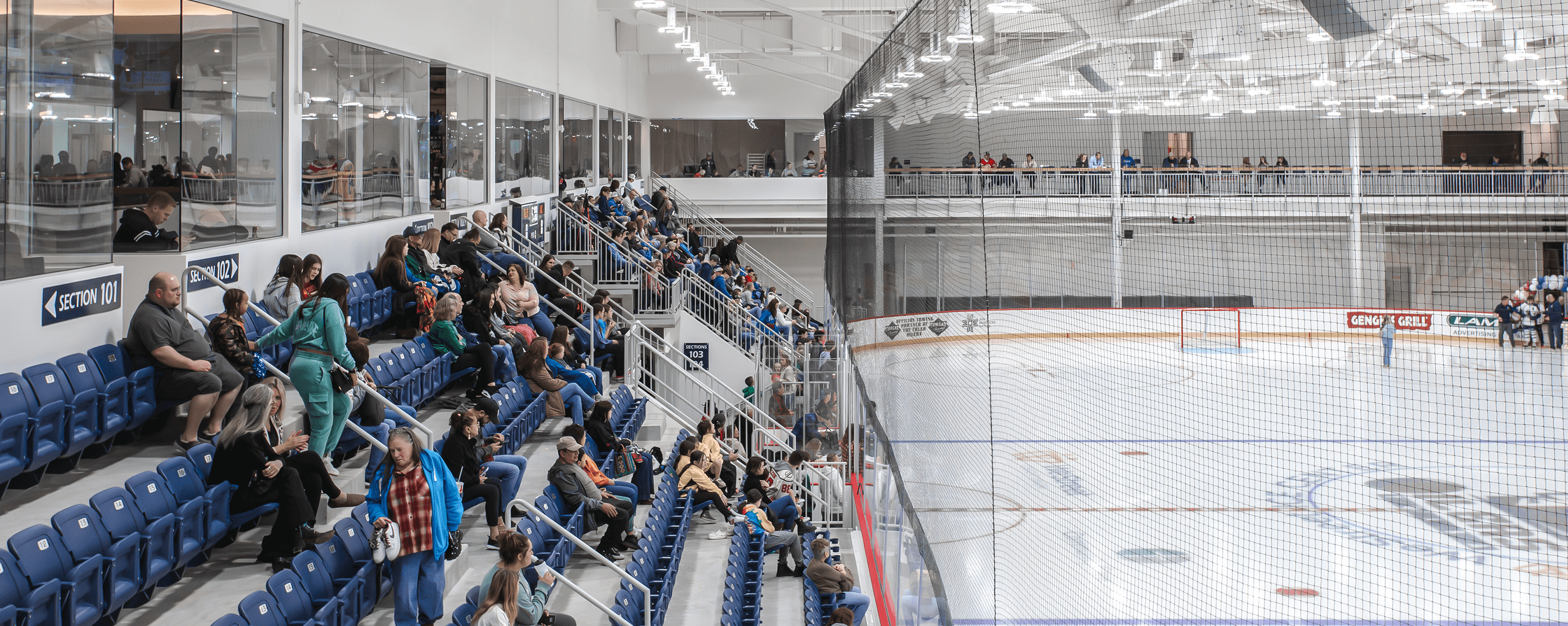 People sitting in stands in an ice hockey rink.