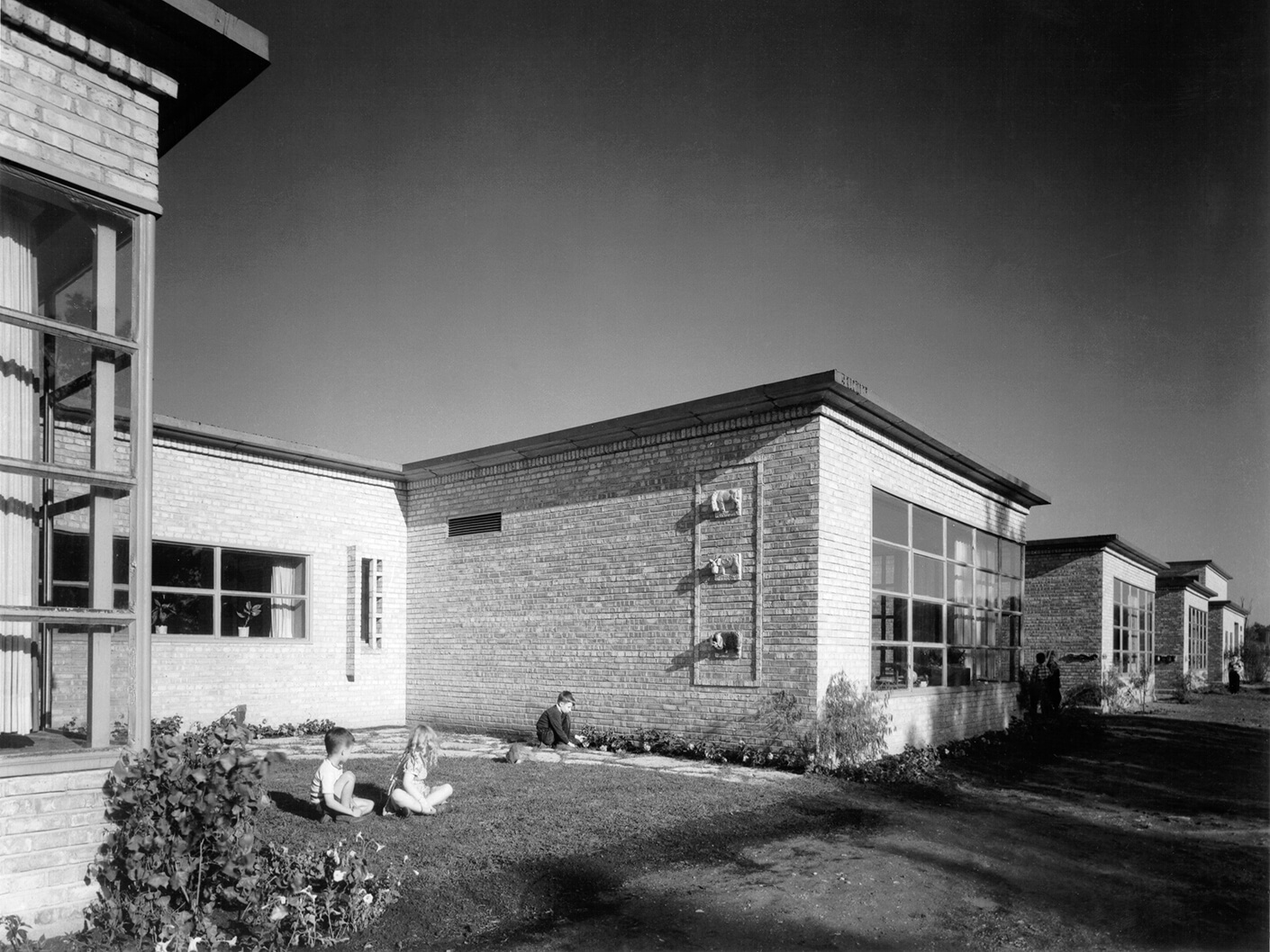 Children sit on the lawn outside of an elementary school