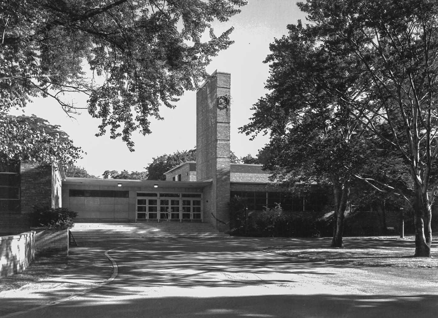 Historical photo of a brick school with an off-centered clock on the facade