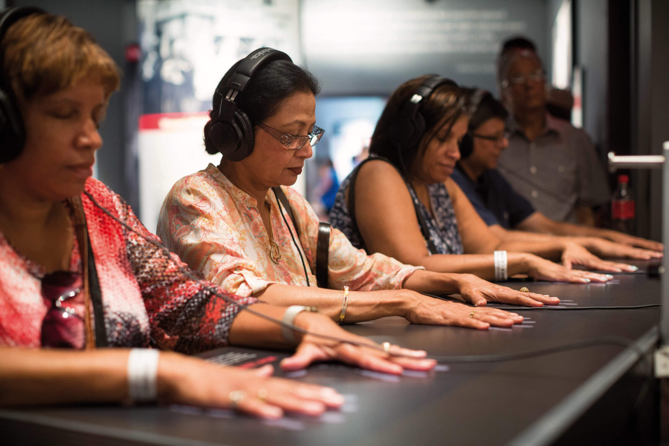 Three women participating in a seated audio exhibit.