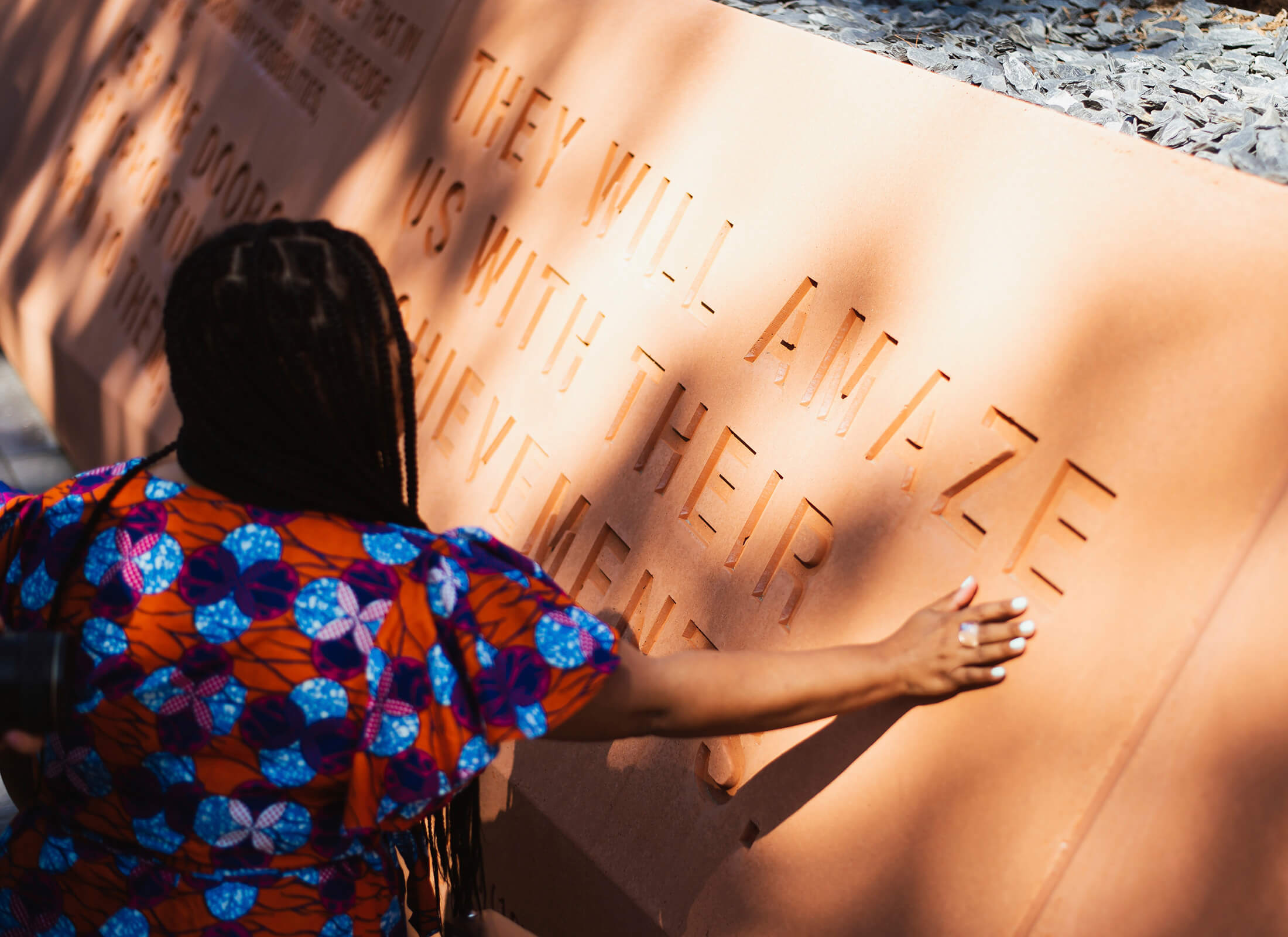 A woman touching the red clay walls.