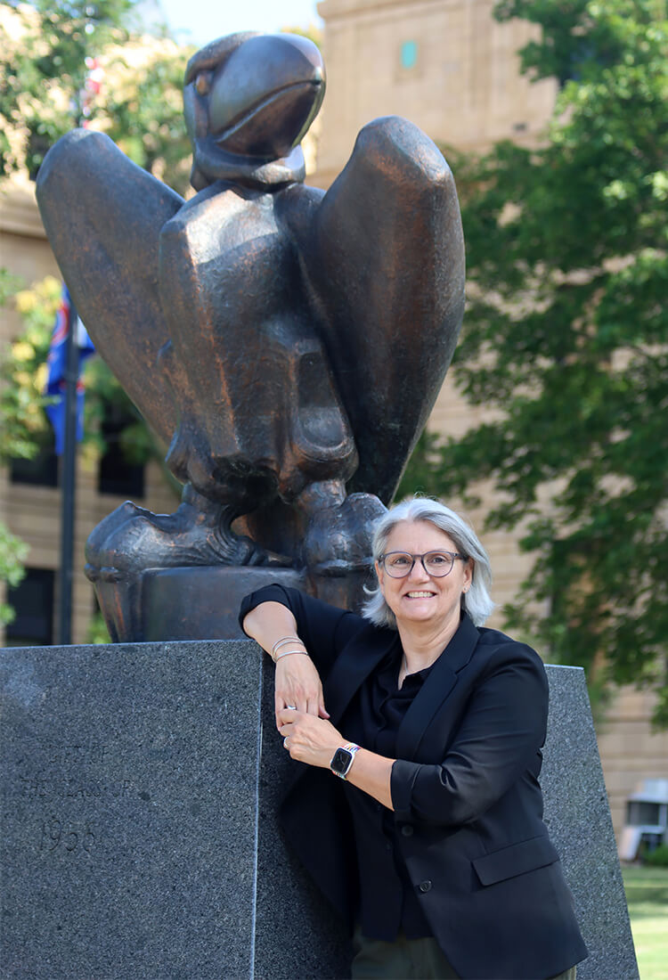 Dr. Barbara Bichelmeyer stands in front of a statue of the school mascot.