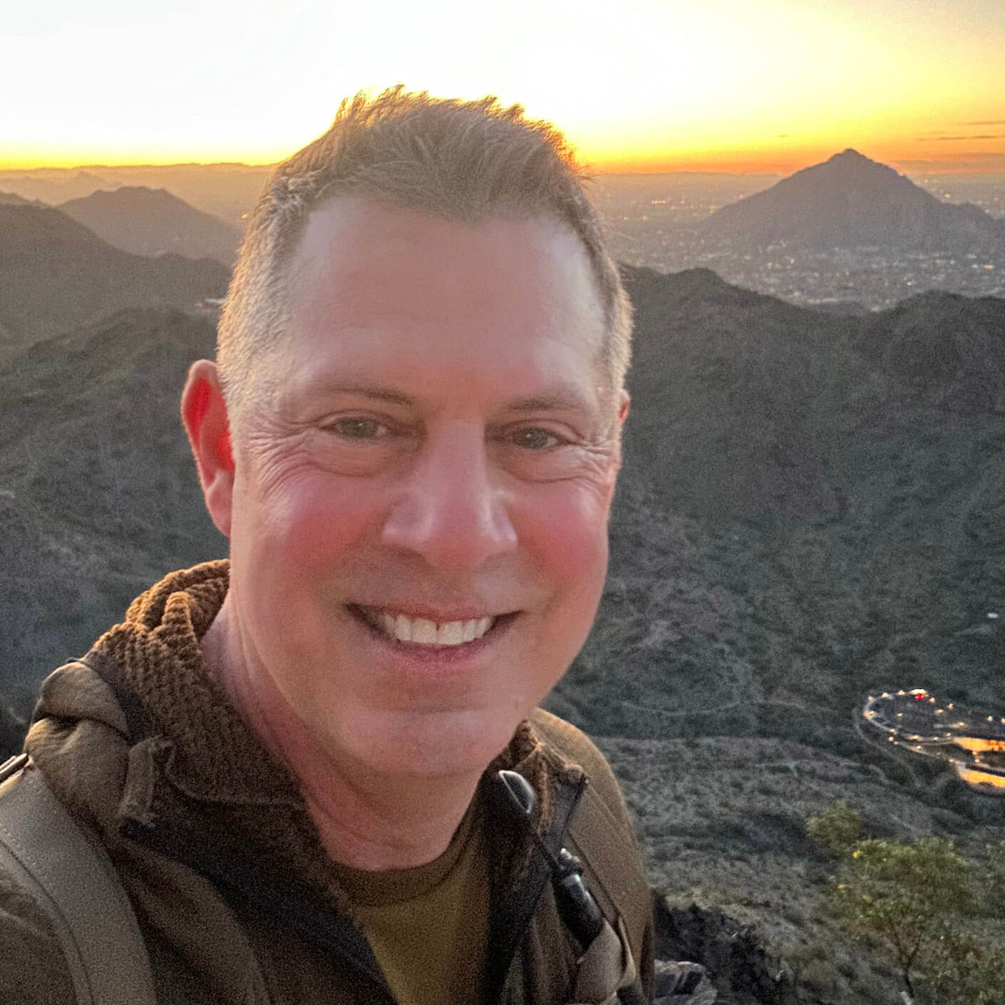 Rudy smiling in a selfie on a hike with a mountainous backdrop