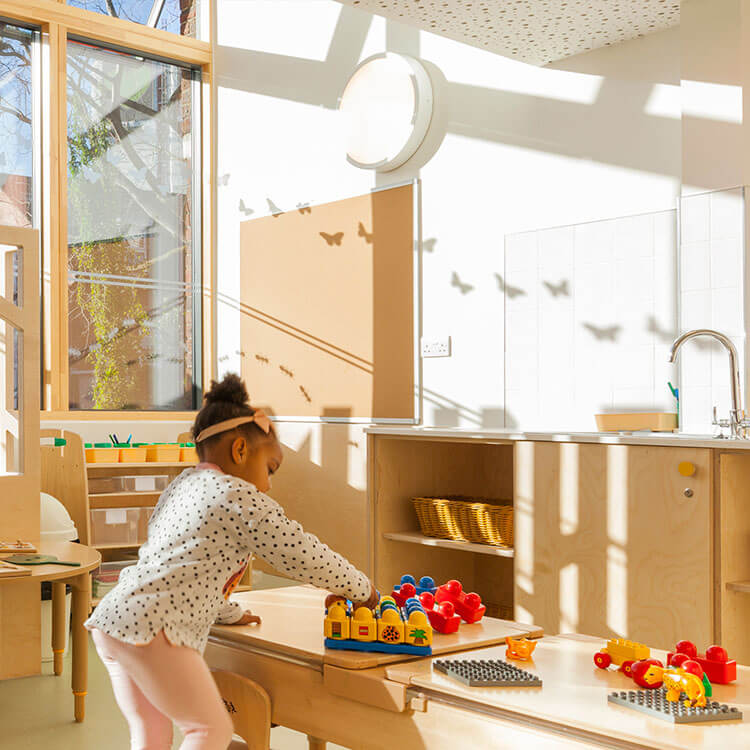 a girl plays at a table in a light-filled nursery