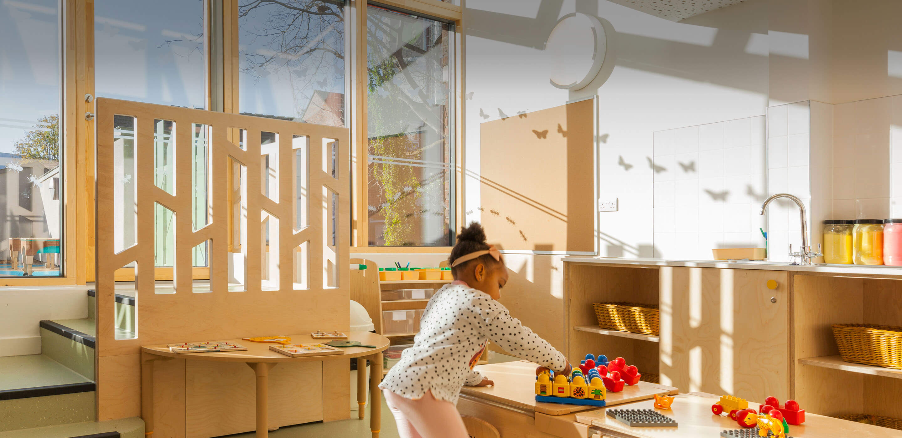 a girl plays at a table in a light-filled nursery