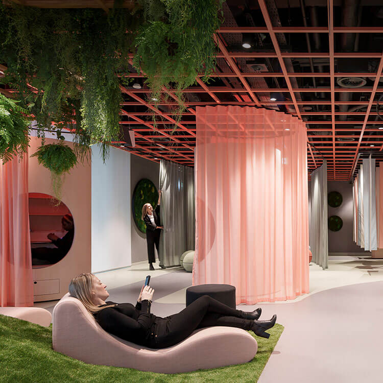 An office space filled with plants and pink curtains