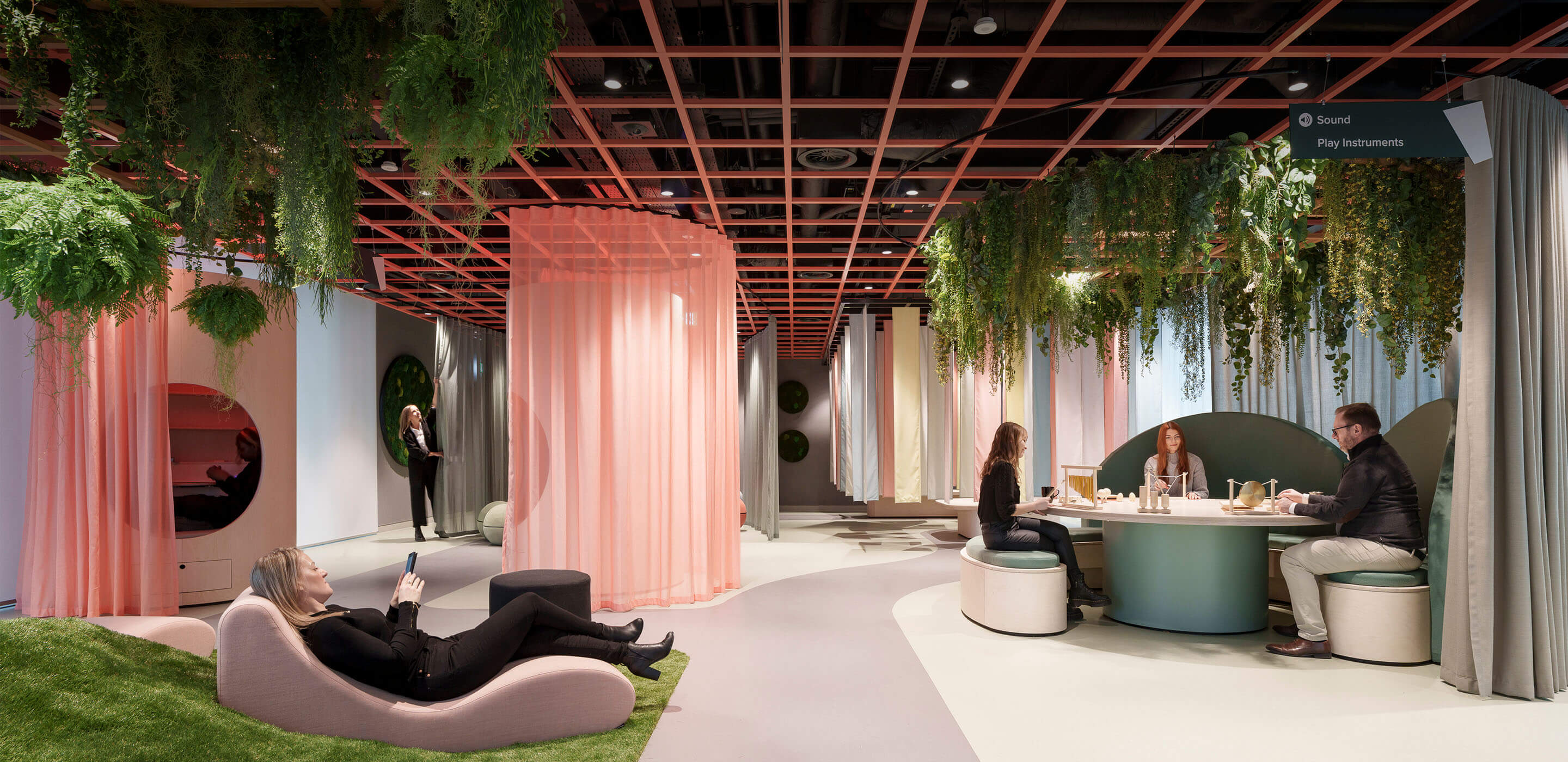 An office space filled with plants and pink curtains