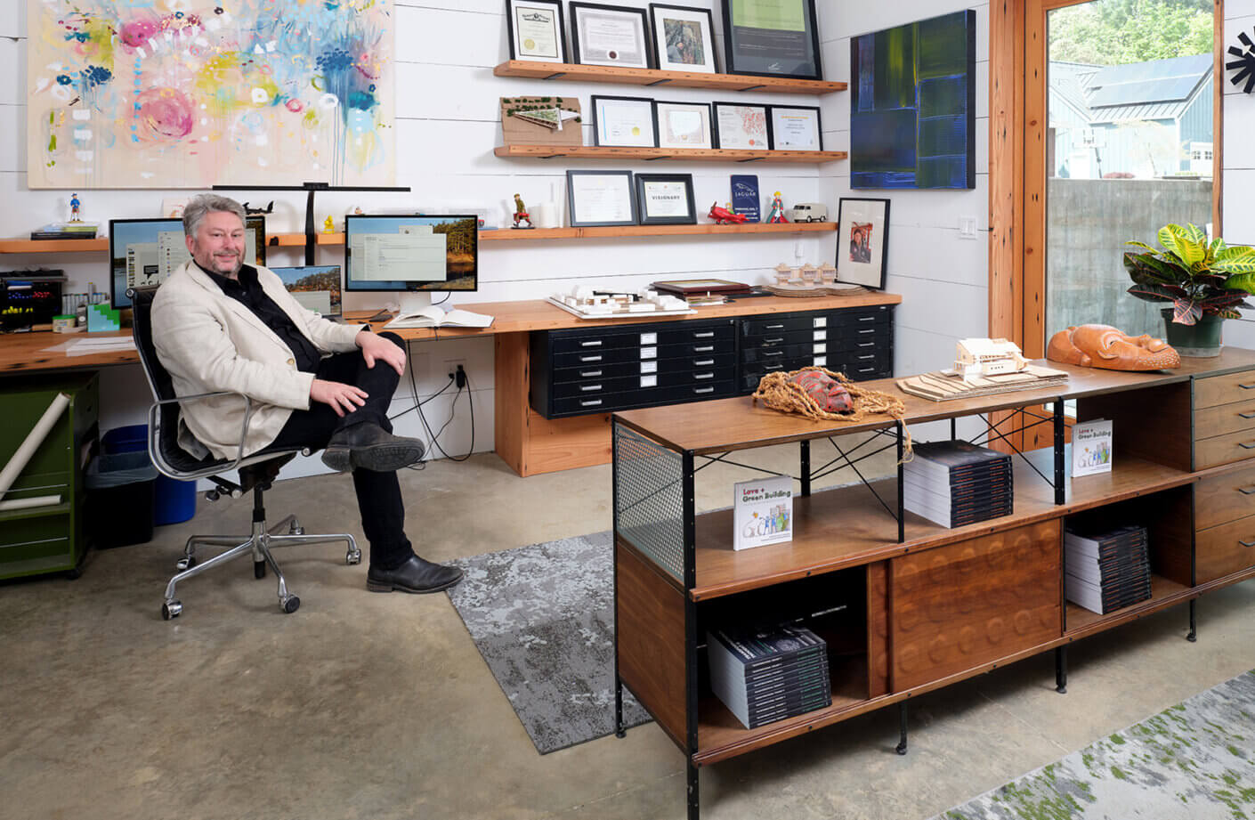 Jason F. McLennan in his office—formerly a coal cellar—now beautifully renovated and featuring a salvaged wood desk and floating shelves.