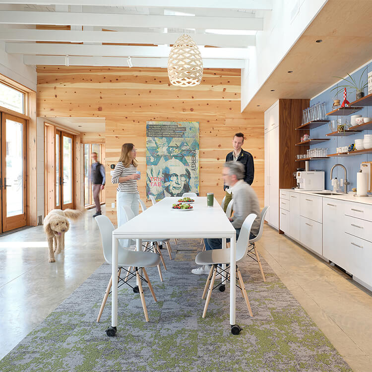 interior of the studio's dining room, with a group of people and a dog gathered around