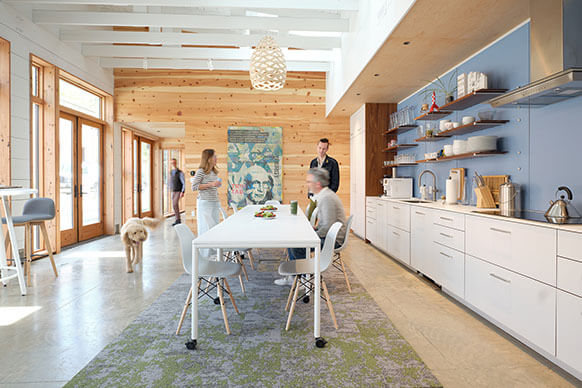 interior of the studio's dining room, with a group of people and a dog gathered around