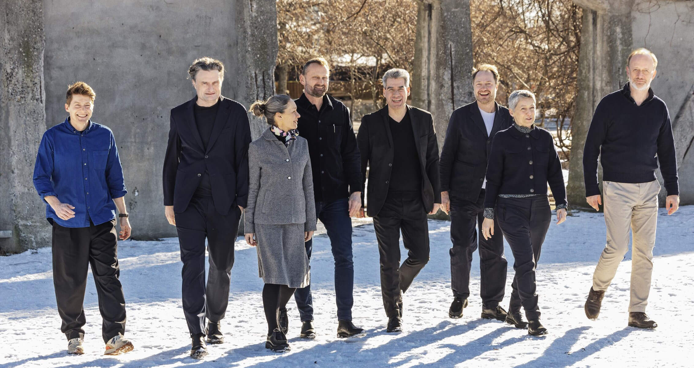 A group of eight people walk in the snow