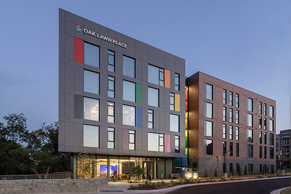 The colorful corner facade of Oak Lawn Place at dusk
