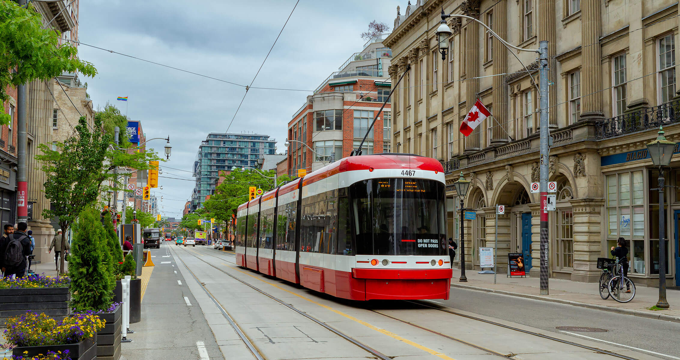 A red streetcar travelling down a street in Toronto