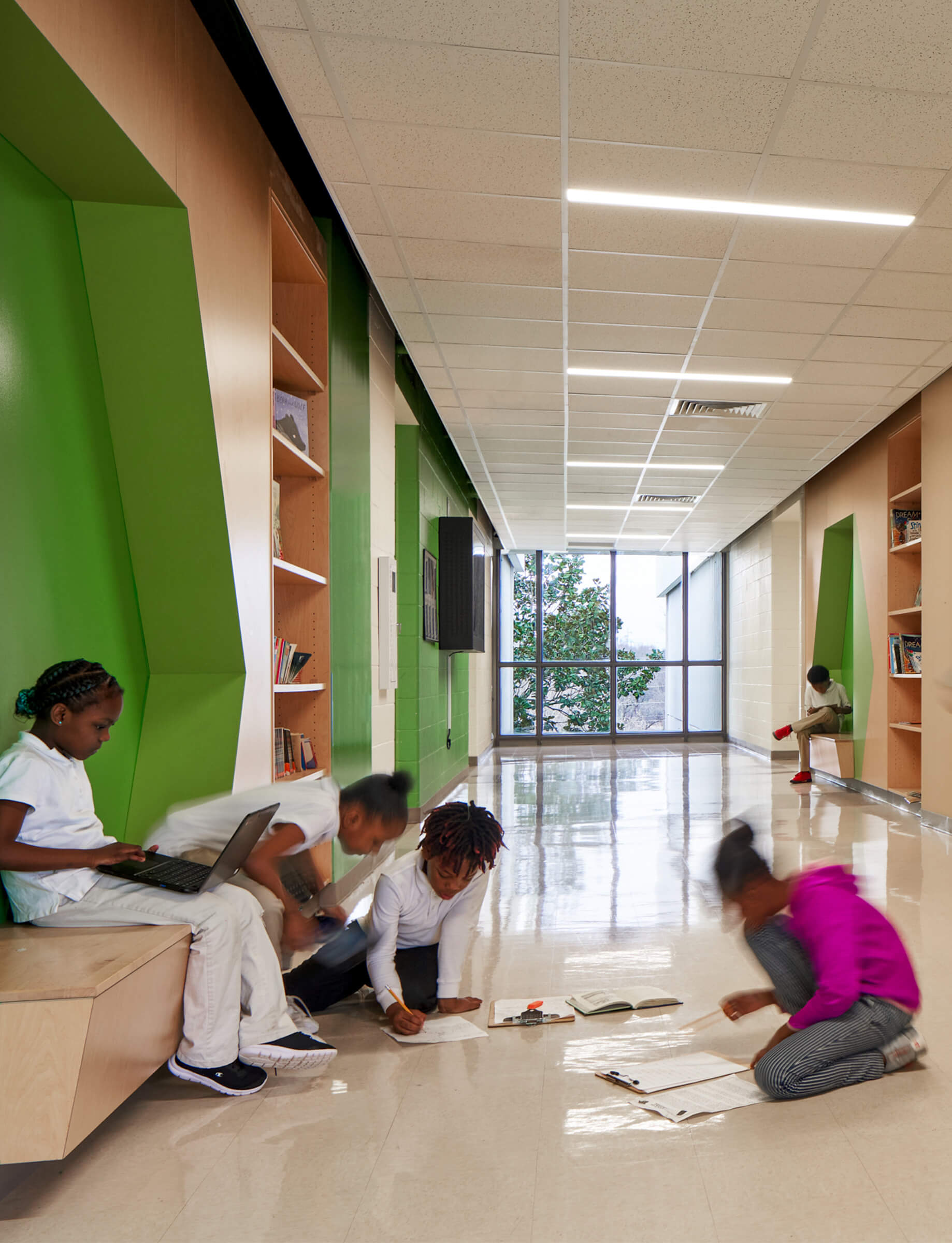 children in writing and talking in a school hallway