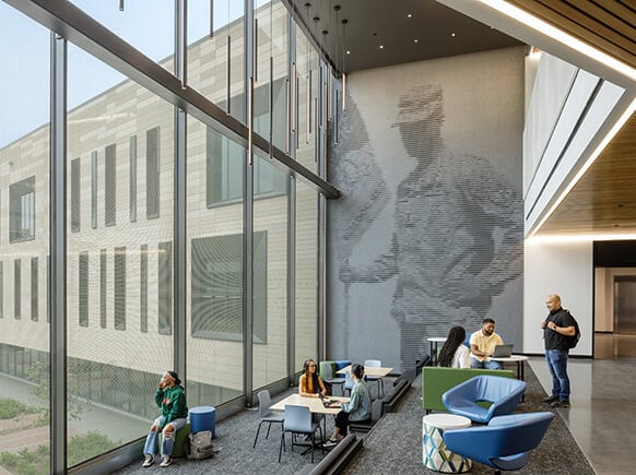Modern office space with large windows, people collaborating and relaxing.