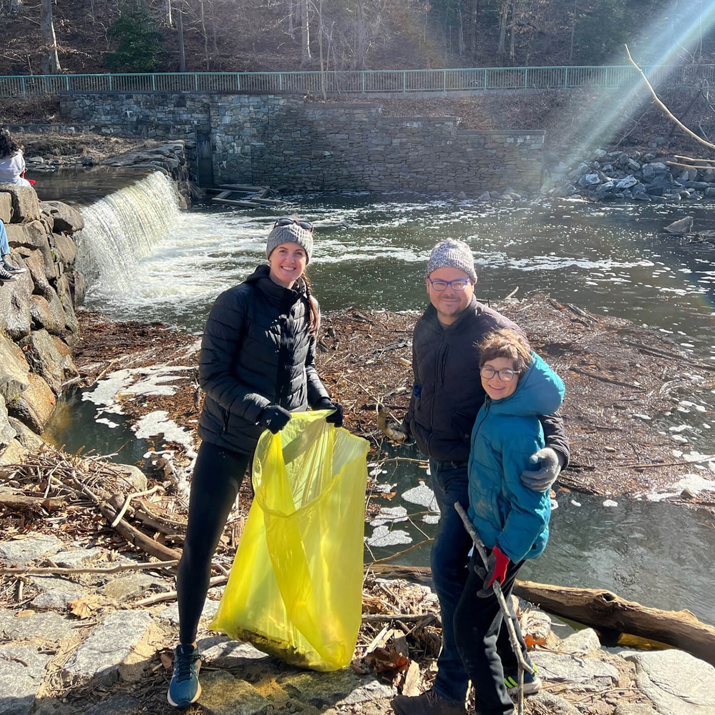 Two adults and a child cleaning up a river bank