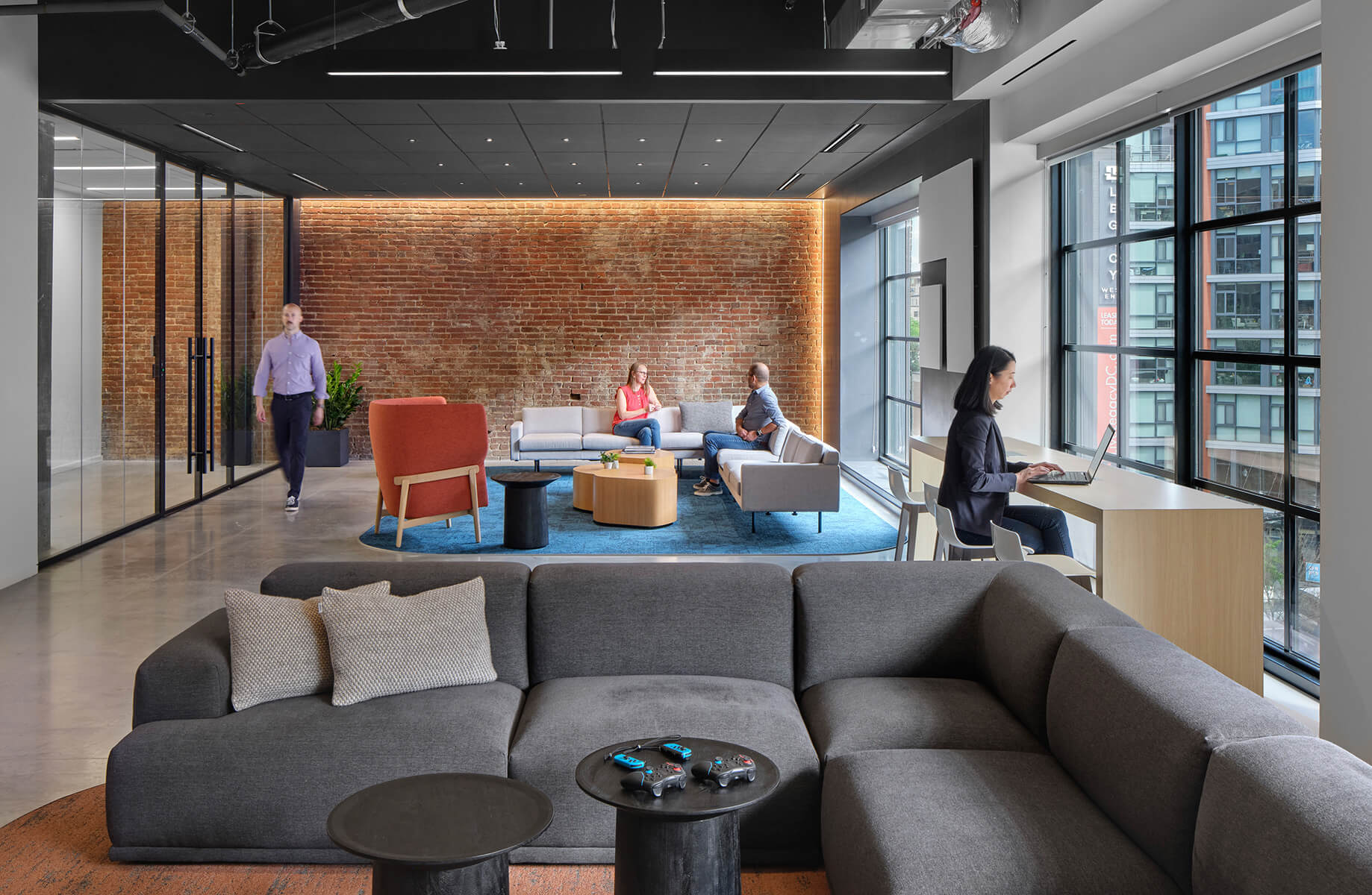 people working in an office with a exposed brick wall in the back