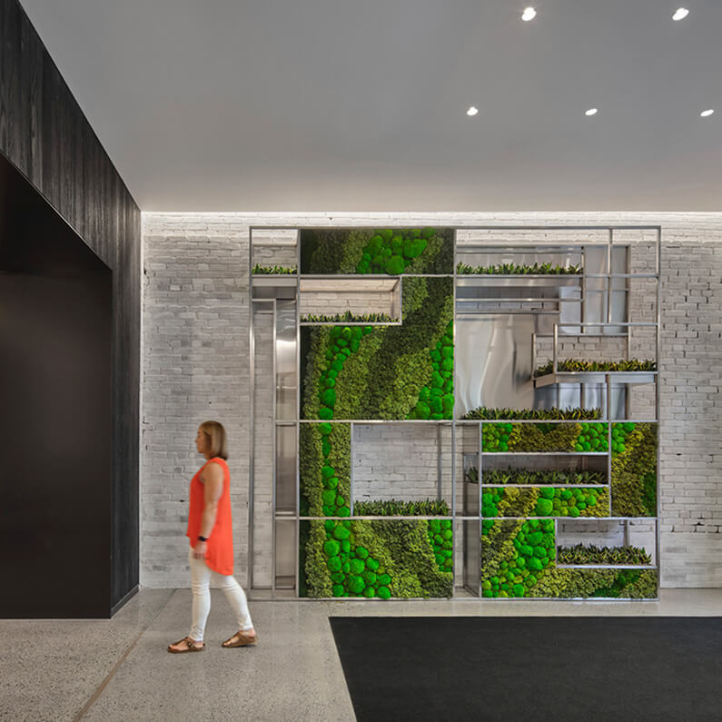 Green wall display with person walking by
