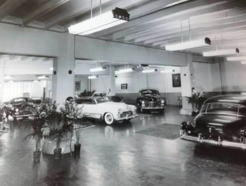 Black and white image of cars in an old showroom