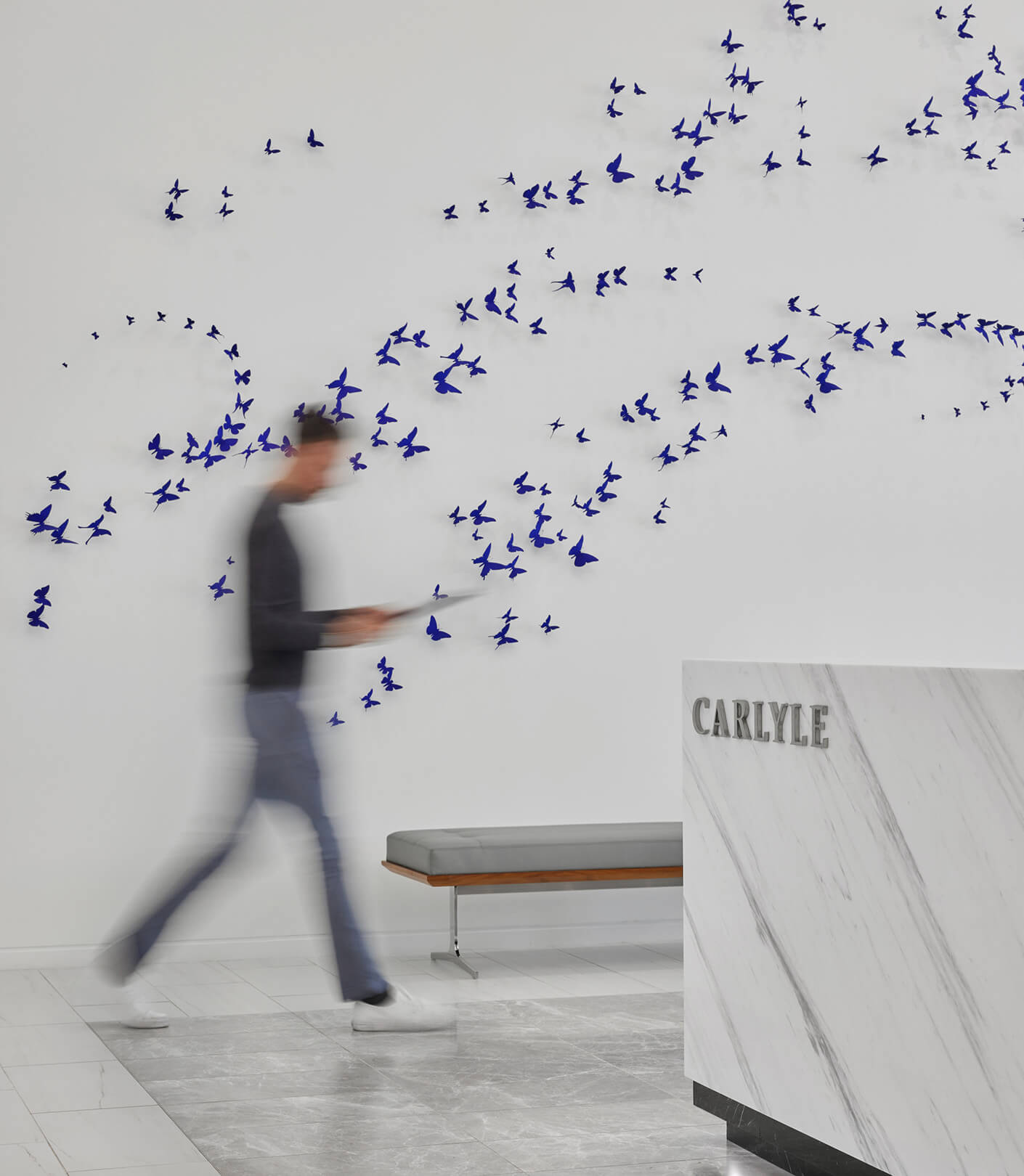 person walking past a branded wall with butterfly art