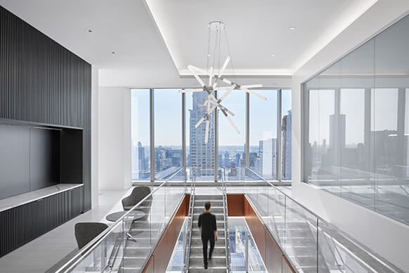 person walking up stairs with views to NYC out a window
