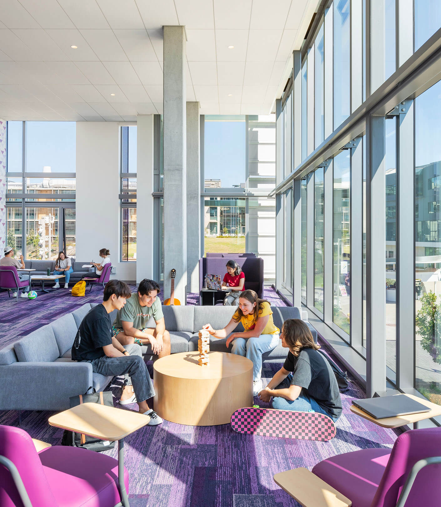 four students sitting in a lounge playing games