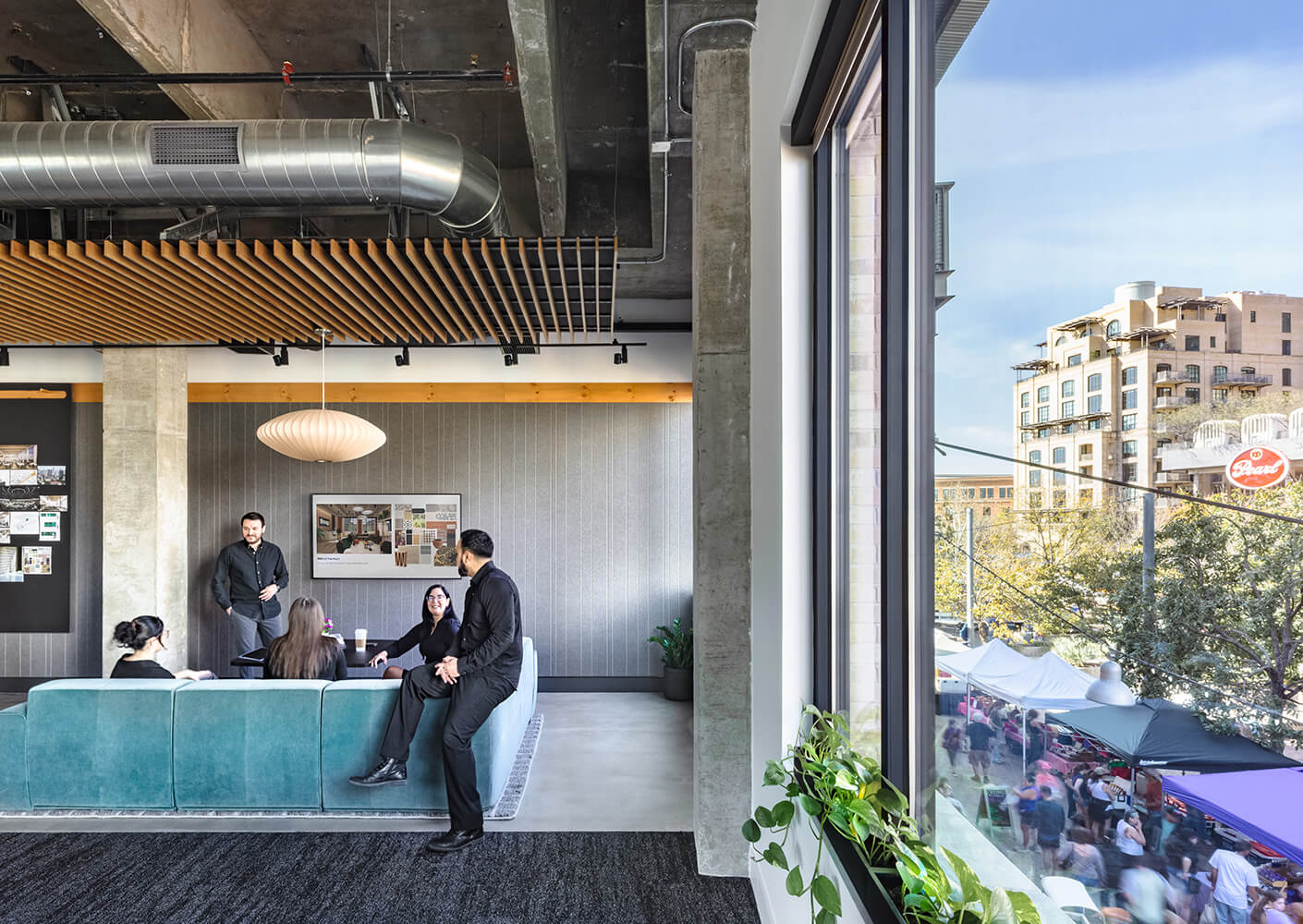 Designers gather on a blue couch next to a large window showing activity outside in the Pearl district