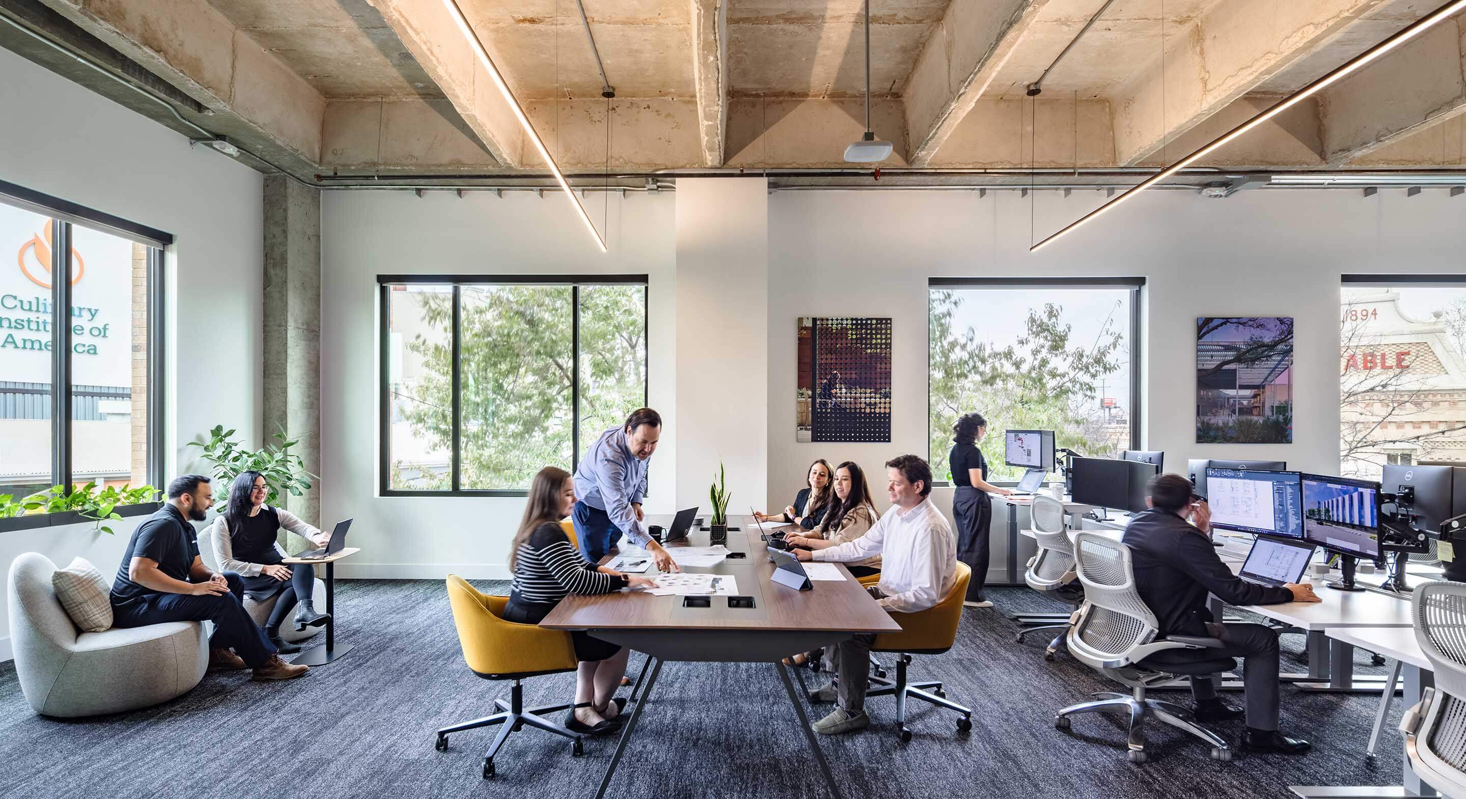Designers work on a communal couch by a large window, bathed in abundant natural light