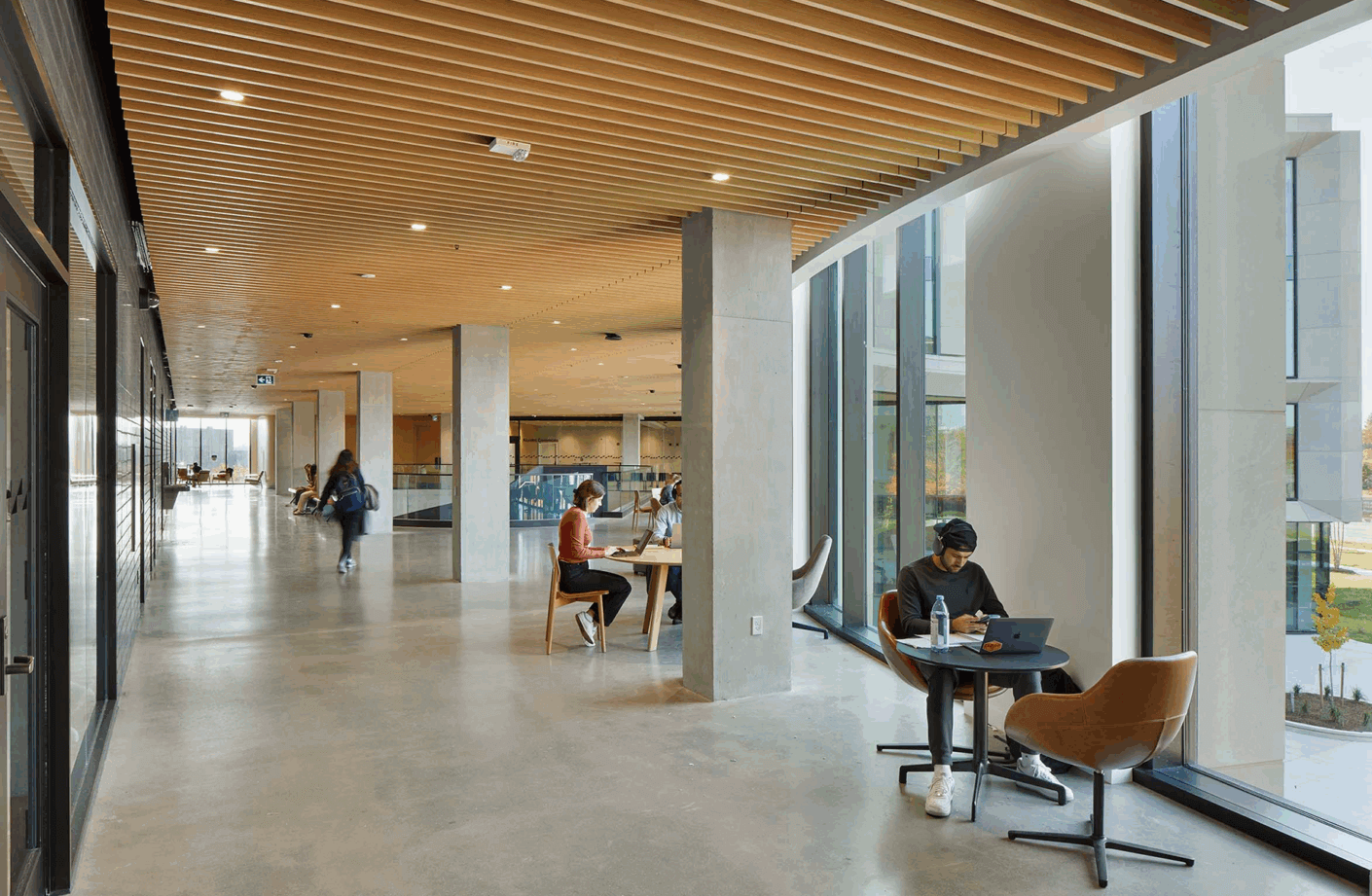 A broad, daylit corridor with views to the campus supports informal breakout and study outside of classrooms and labs.