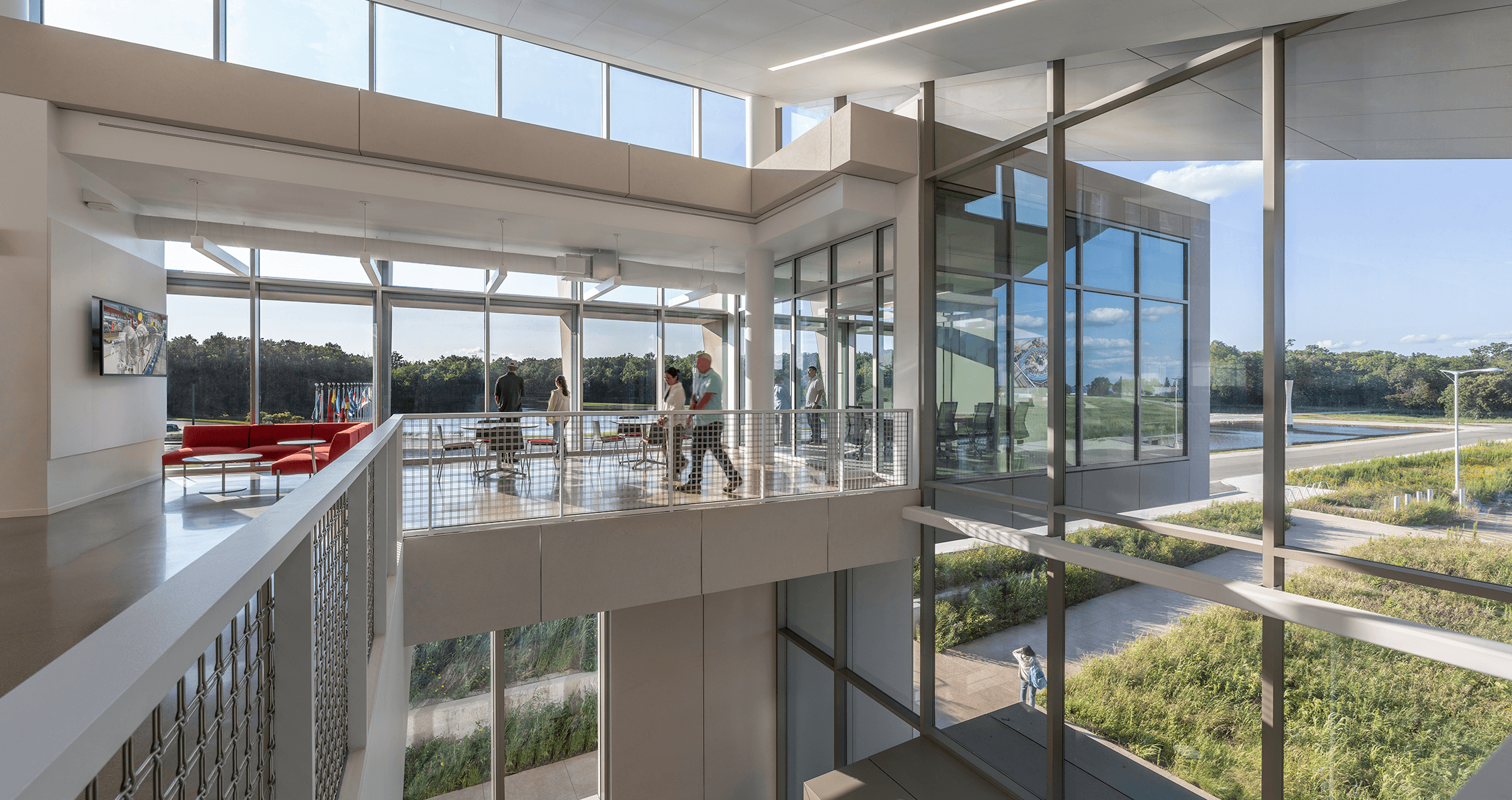 Bright interior space featuring large windows, open areas, and people interacting in a contemporary architectural setting.