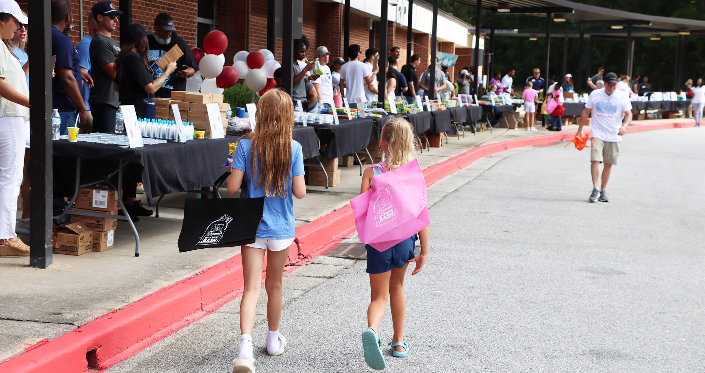Two kids walking down an awning with tables of school supplies