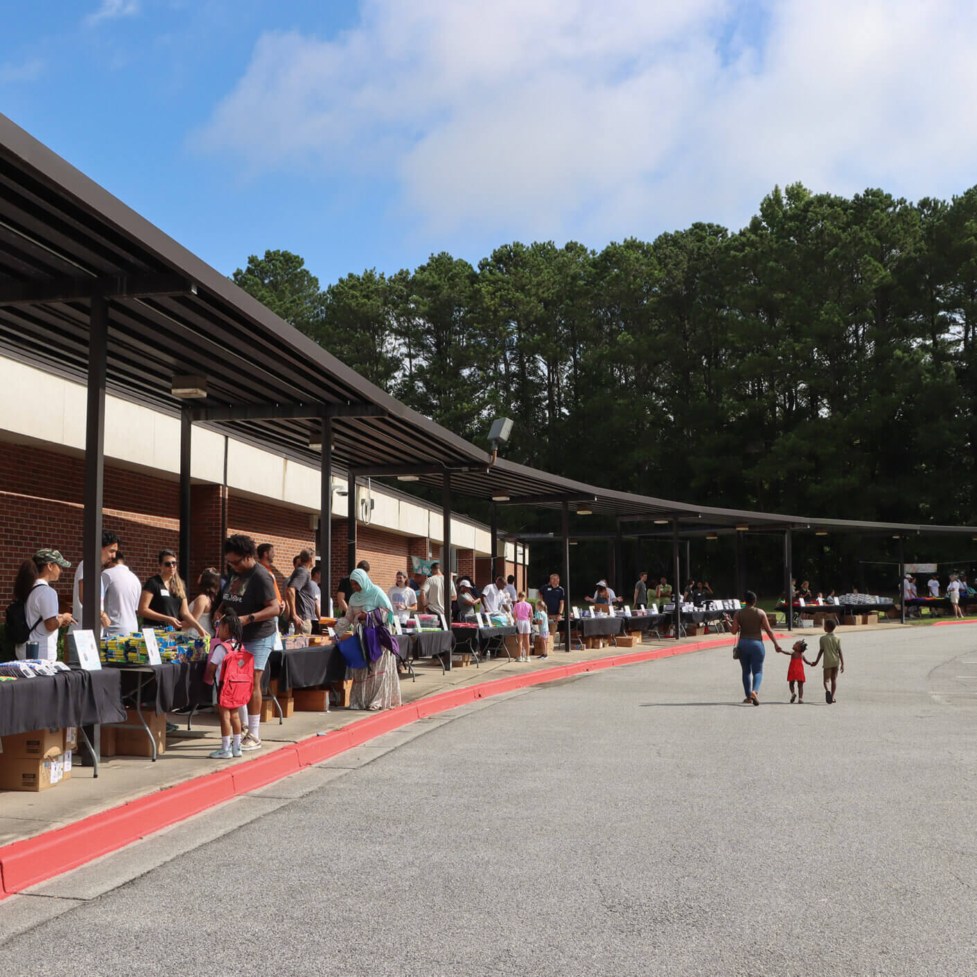 an awning with people behind tables and giving school supplies