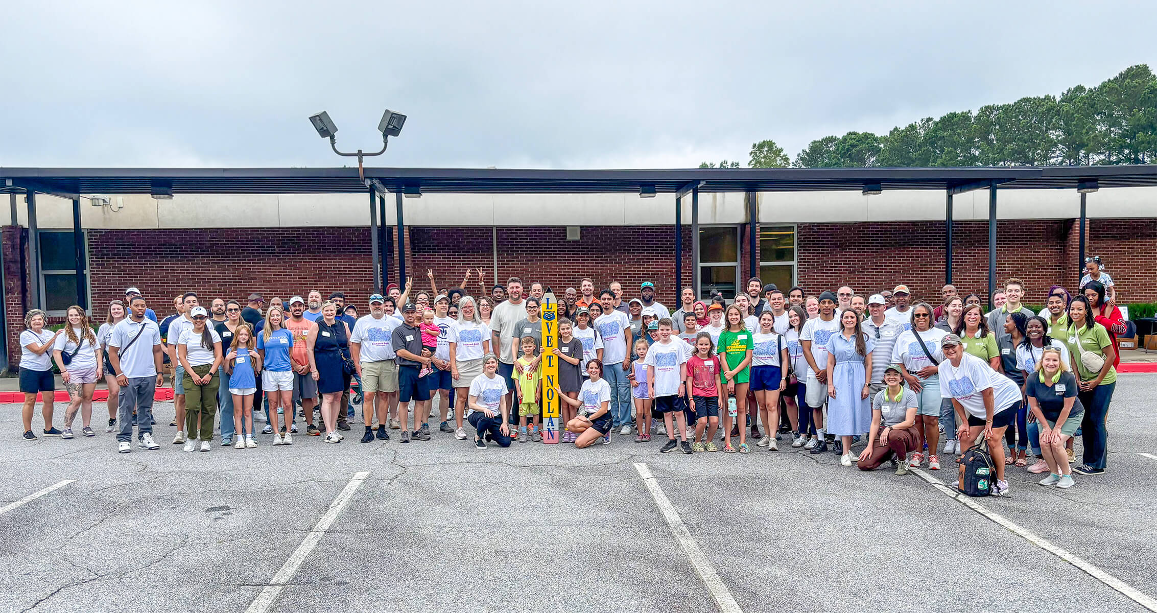 a group photo of people in front of a school