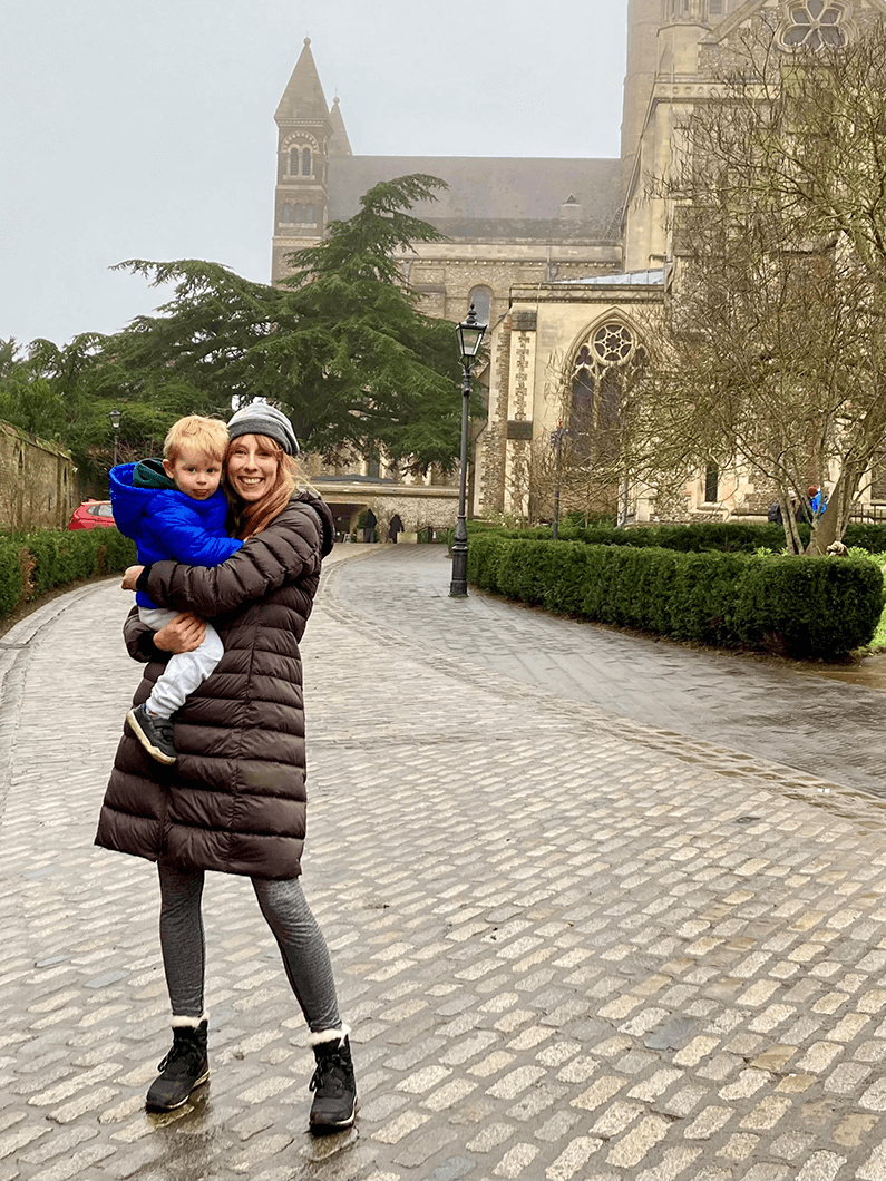 Woman holding child in front of church on a foggy day.