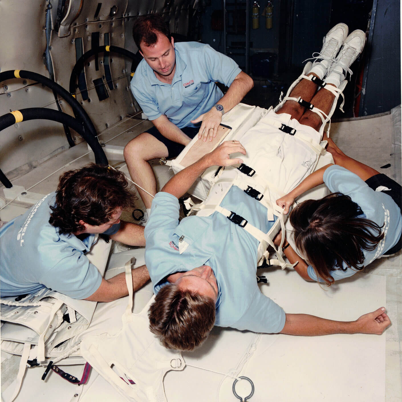 four men working on medical stretcher in zero gravity airplane