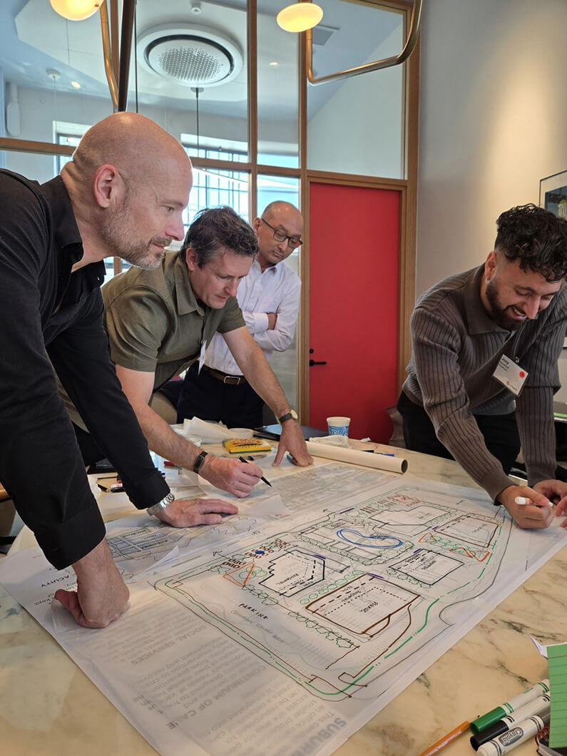 Four people collaborating on architectural plans in a modern office.