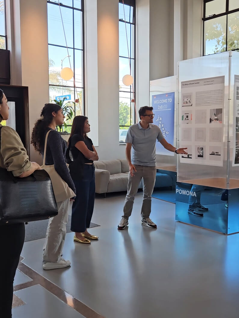 Group of people discussing exhibition displays in a modern lobby with large windows.