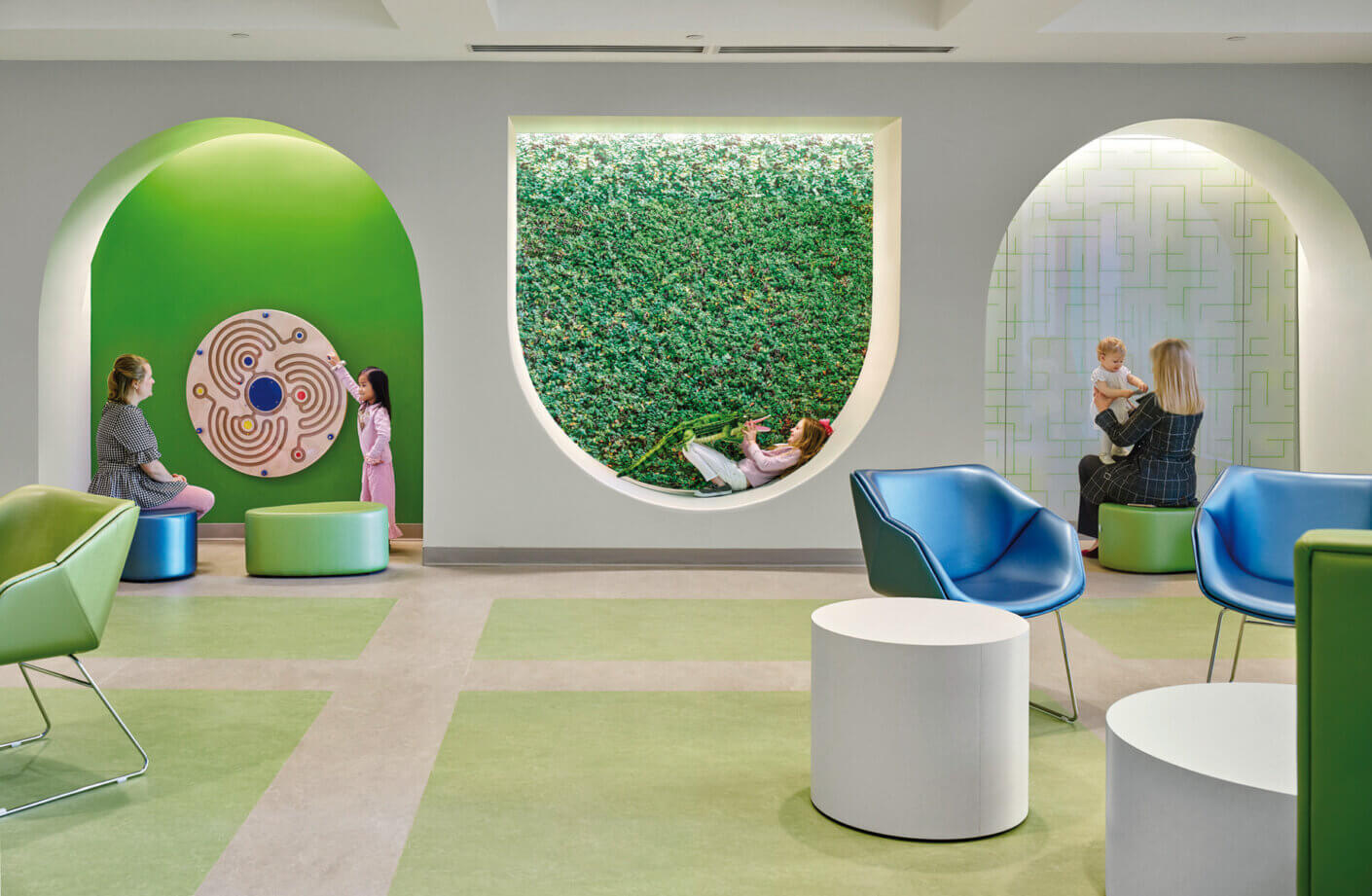 Modern children's play area with interactive wall panels, circular seating, and vibrant green accents.
