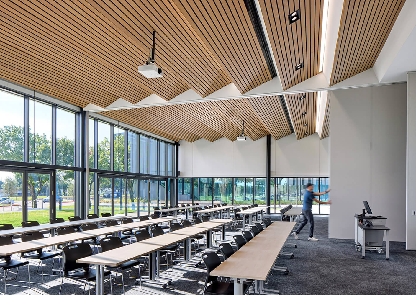 Modern classroom with wooden ceiling, large windows, and flexible seating arrangement for collaborative learning.