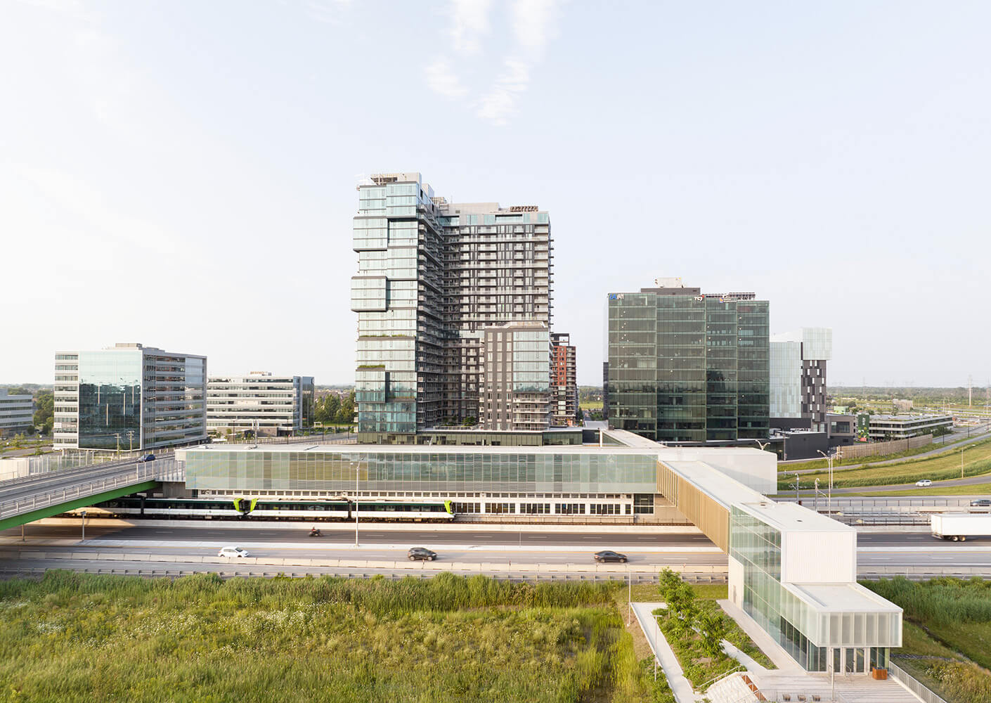 Modern office buildings and highway view during daytime next to a metro station.