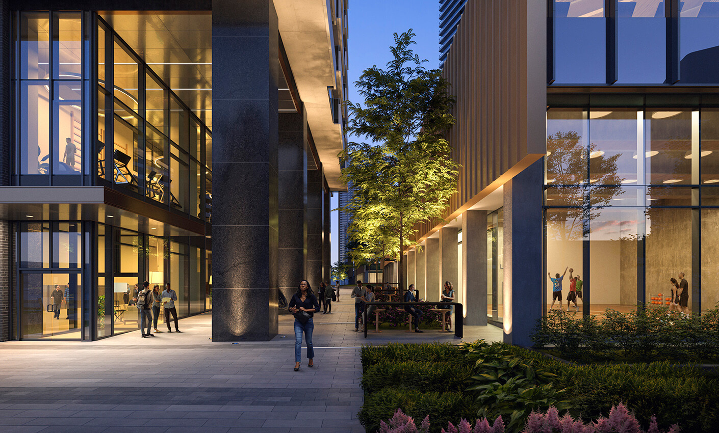Modern urban building at dusk with people walking and relaxing outside, showcasing illuminated windows and greenery.