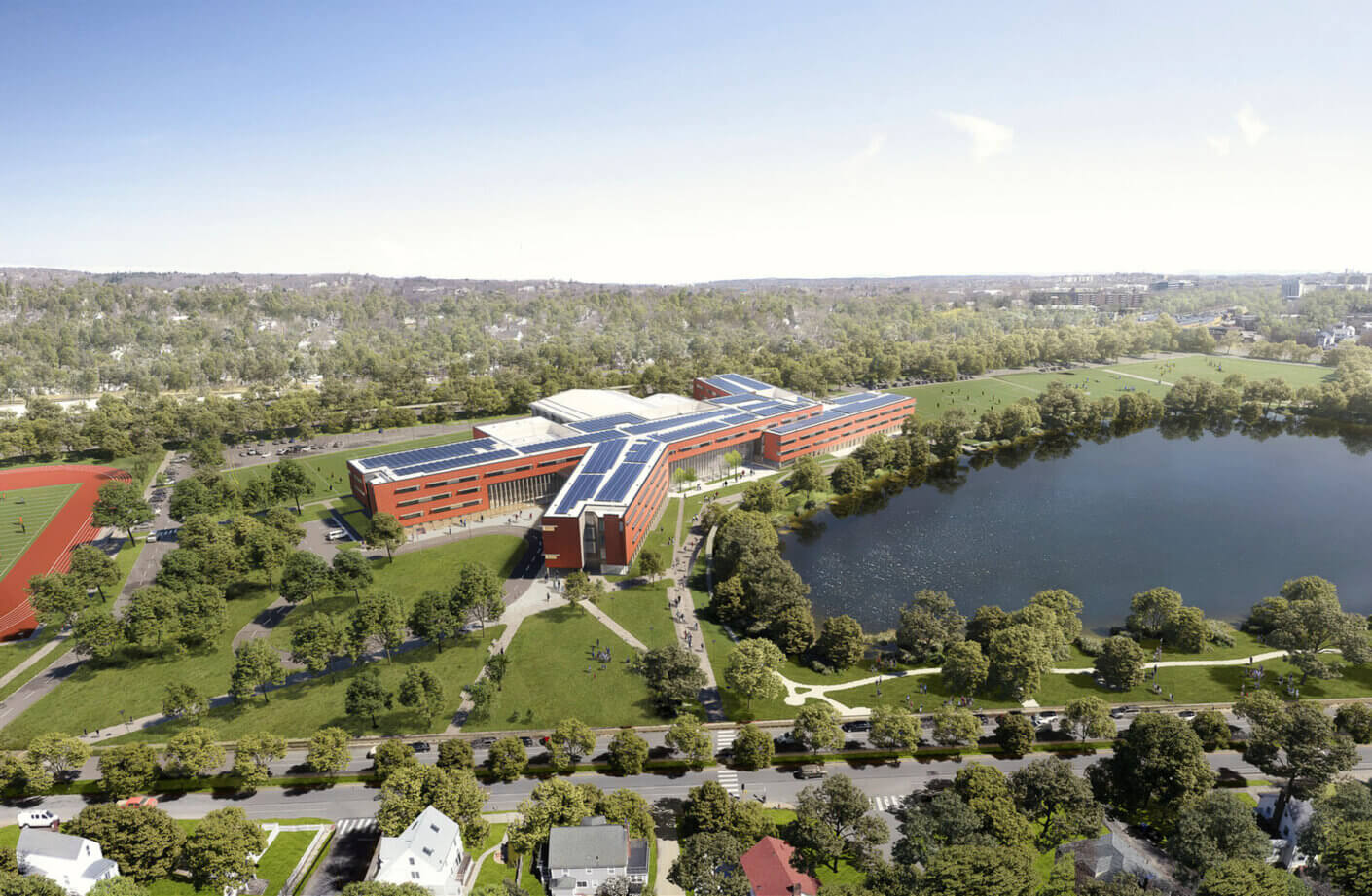 Aerial view of a modern campus with solar panels, sports fields, and a scenic lake surrounded by lush greenery.