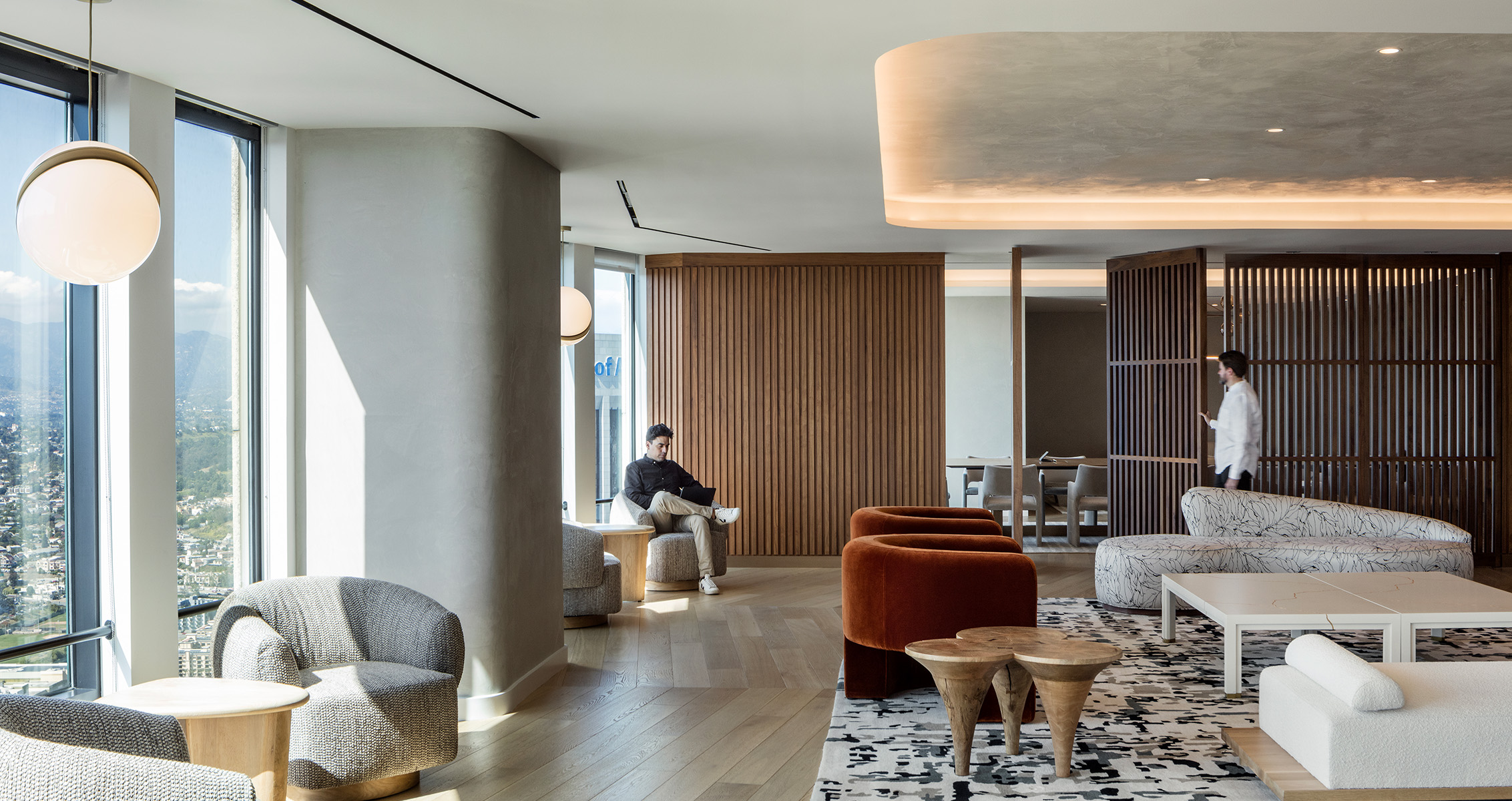 Modern seating area with floor-to-ceiling windows, wooden accents, and stylish furniture. Spacious and elegant design.