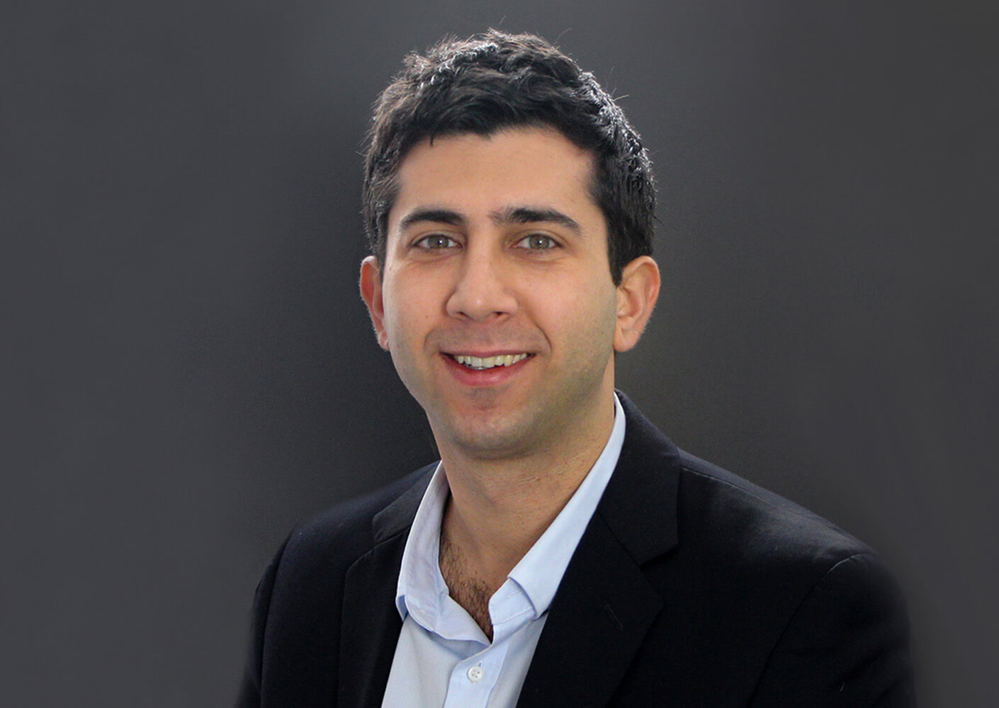 Smiling man in a suit against a dark background, portrait photo.