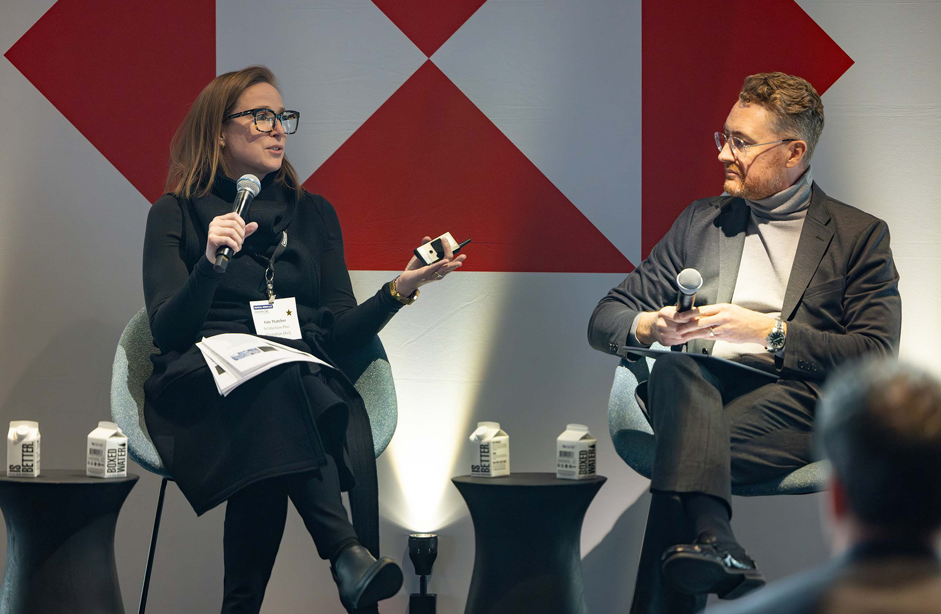 Professionals in a panel discussion with microphones, sharing insights at a conference.