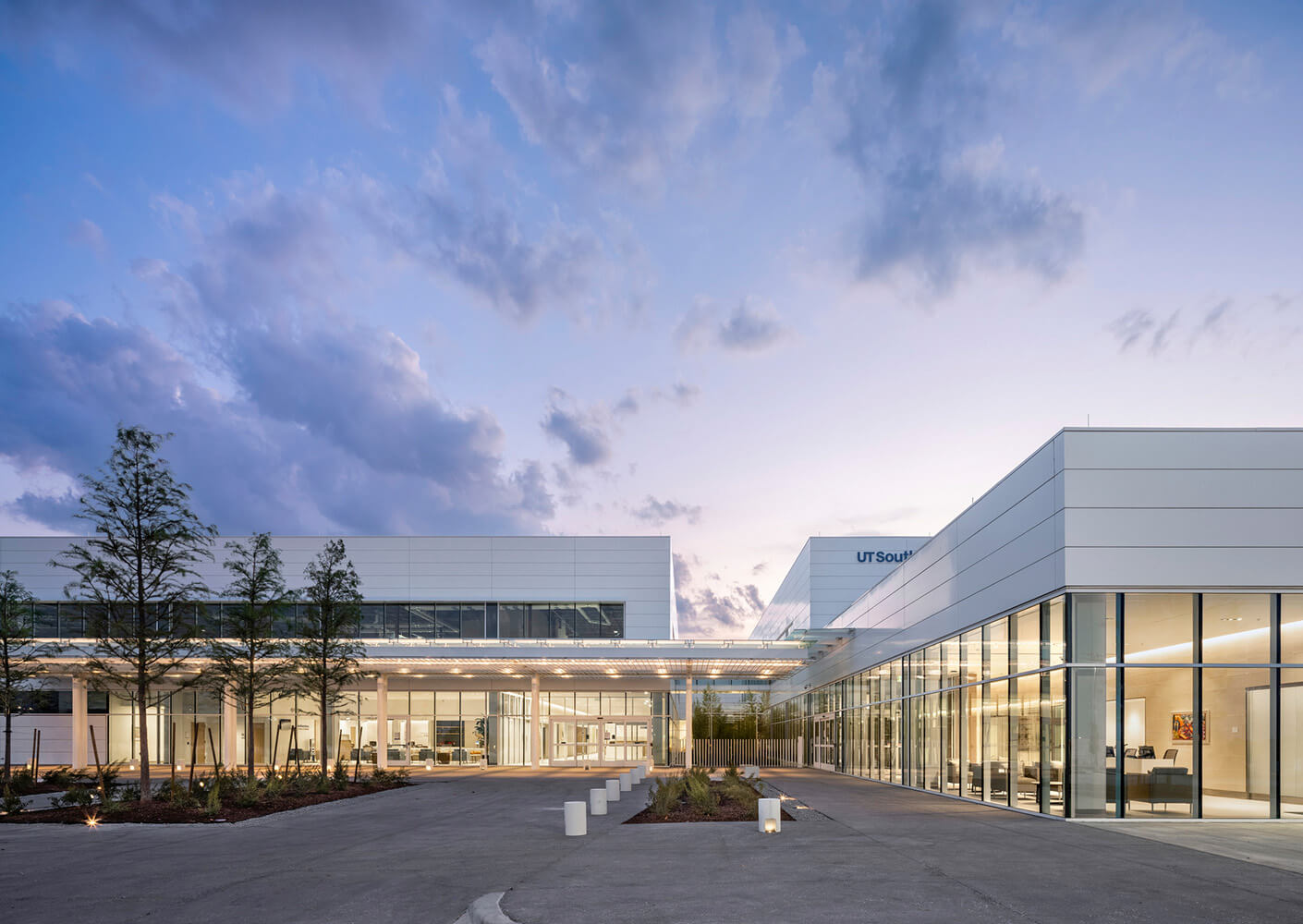 Modern building exterior at dusk with glass facade and pathway.