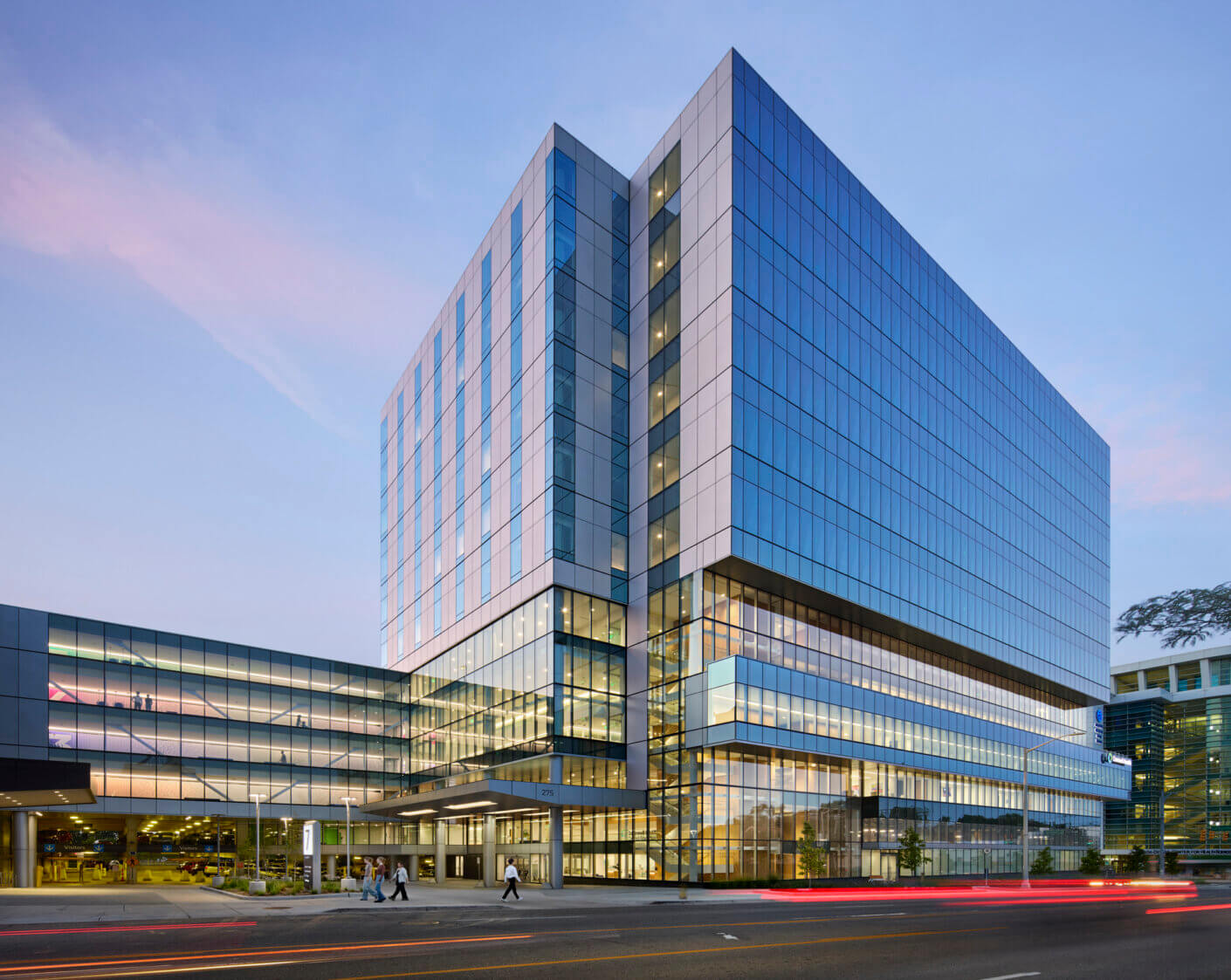 Modern glass office building at dusk with street view.