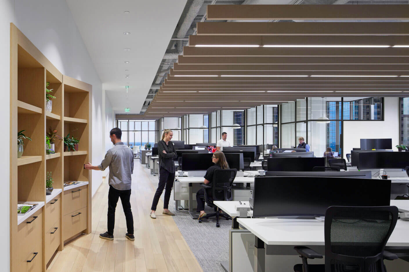 Modern open-plan office with people working at desks and collaborating.