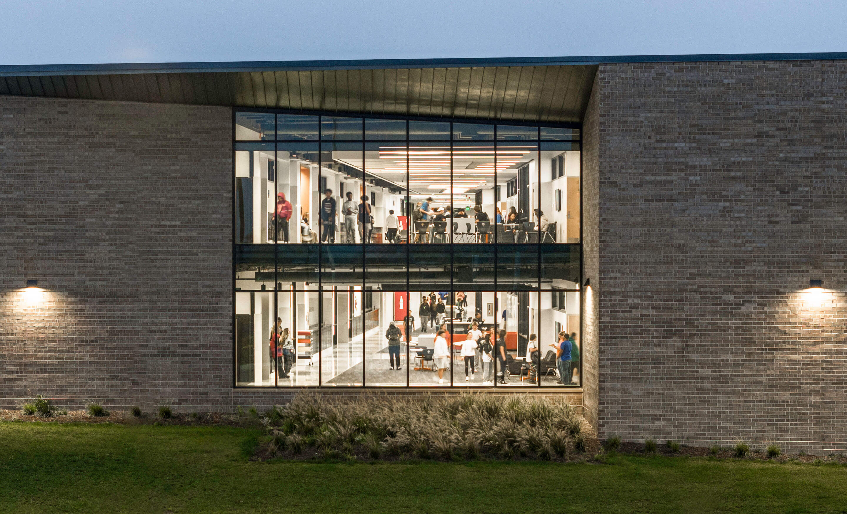 Modern building at night with people inside, large windows visible.